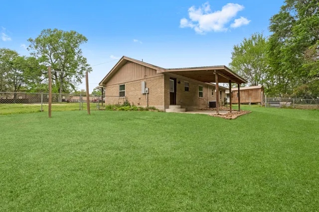 a view of a house with a big yard and large trees
