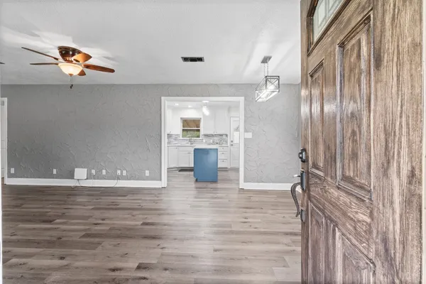 a view of a livingroom with wooden floor and a kitchen space