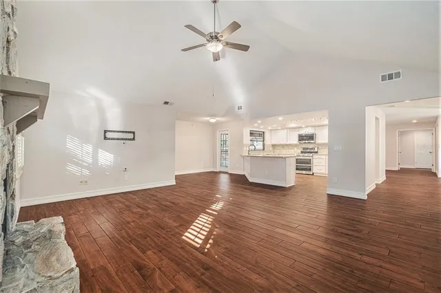 an empty room with wooden floor fireplace and windows