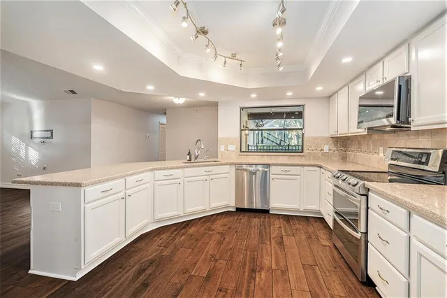 a view of empty room with wooden floor and chandelier