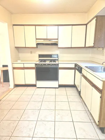 a kitchen with a stove a refrigerator and a white cabinets