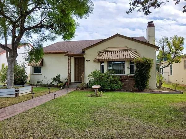 a view of a house with garden and a tree