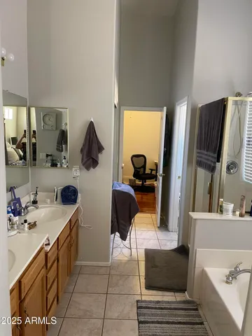 a en suite bathroom with a double vanity sink a mirror and bathtub