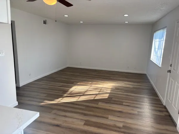 a view of empty room with wooden floor and fan