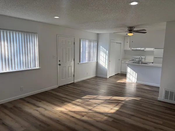 a view of empty room with wooden floor and fan