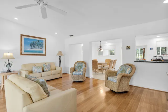a living room with furniture and a dining table with wooden floor