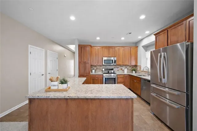 a kitchen with stainless steel appliances granite countertop a refrigerator a sink and a stove