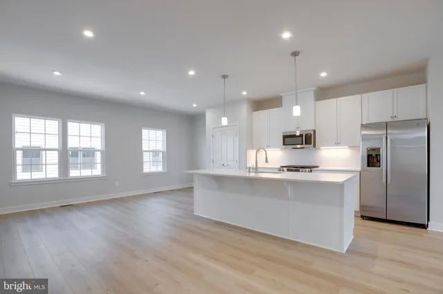 a large kitchen with stainless steel appliances a large counter top a sink and a refrigerator