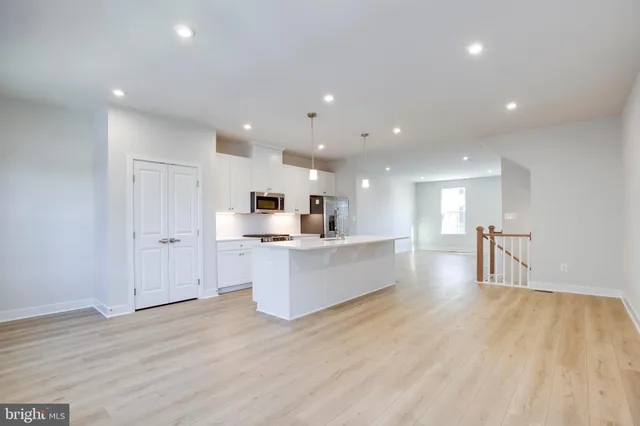 a large white kitchen with kitchen island a sink a center island stainless steel appliances and a fireplace
