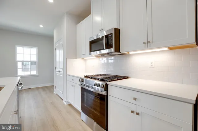 a kitchen with stainless steel appliances white cabinets and a stove top oven