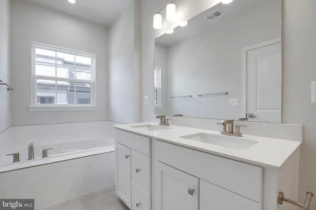 a bathroom with a sink double vanity granite tub and a mirror