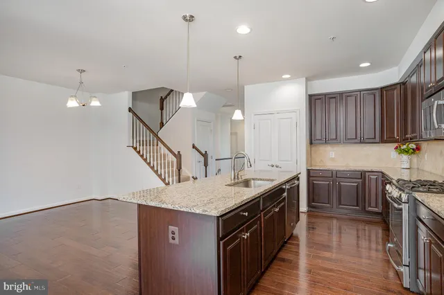 a large kitchen with stainless steel appliances granite countertop a refrigerator a sink dishwasher a stove and white countertops with wooden floor