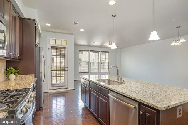 a kitchen with a kitchen island a sink stainless steel appliances and wooden floor