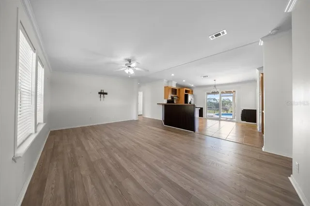 a large kitchen with kitchen island granite countertop a refrigerator a stove top oven a sink a dining table and chairs with wooden floor