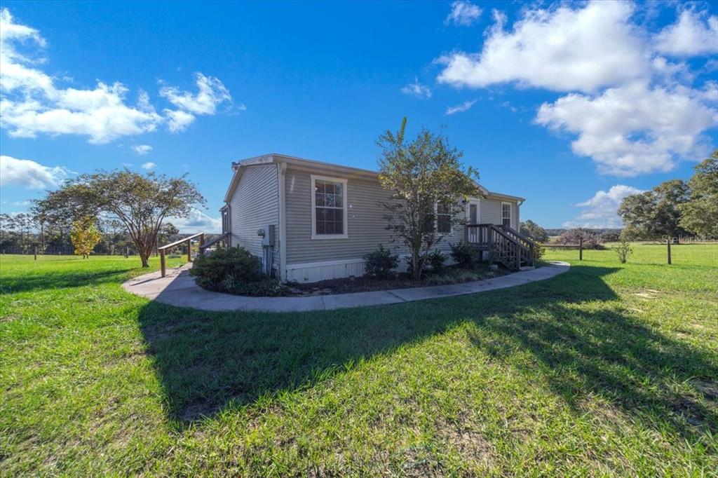 17355 Southeast 260th Avenue Road Umatilla, FL 32784 - Photo 9 of 69 a front view of a house with garden and patio
