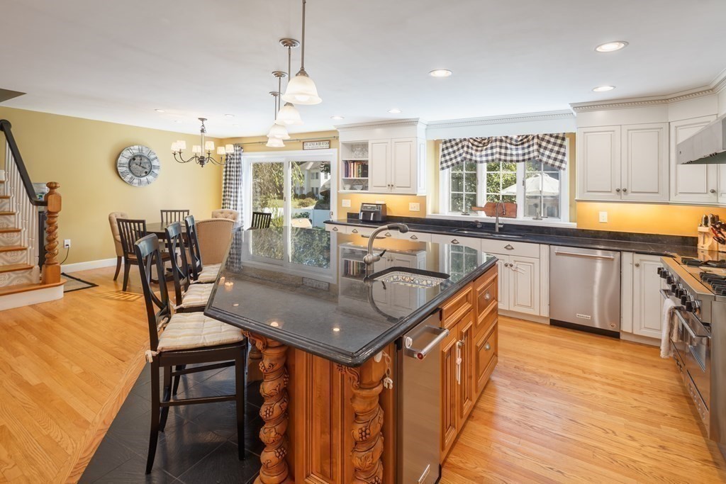 29 Anne Road North Andover, MA 01845 - Photo 11 of 31 a kitchen with stainless steel appliances granite countertop a sink a stove top oven a dining table and chairs with wooden floor