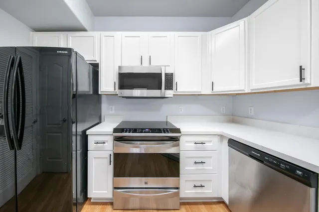 a kitchen with stainless steel appliances white cabinets and a stove a refrigerator with white countertops and cabinets