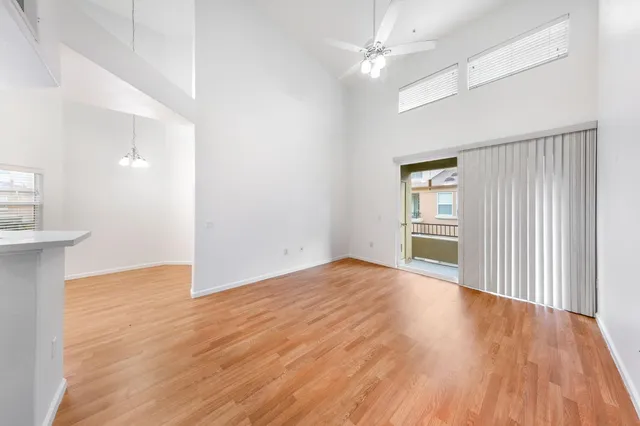 an empty room with wooden floor cabinet and windows