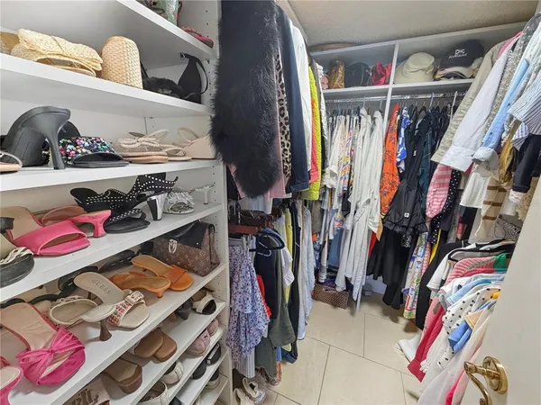 a view of walk in closet with clothes and shoes