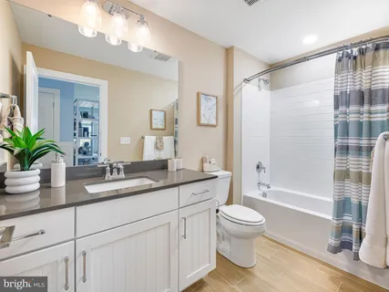 a bathroom with a granite countertop sink a toilet a large mirror and shower