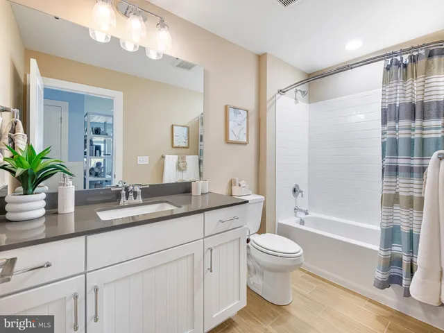 a bathroom with a granite countertop sink a toilet a large mirror and shower