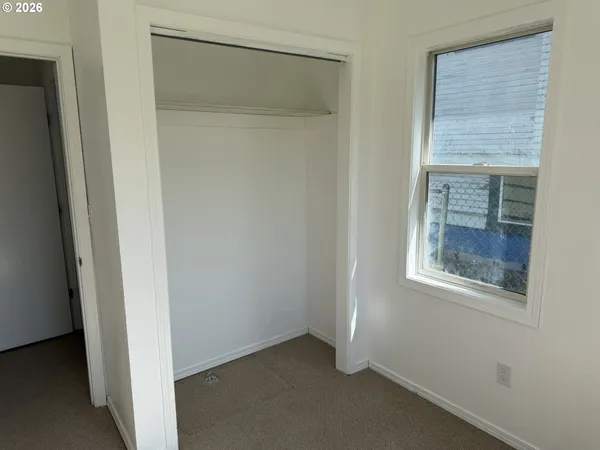 a view of an empty room with closet and windows