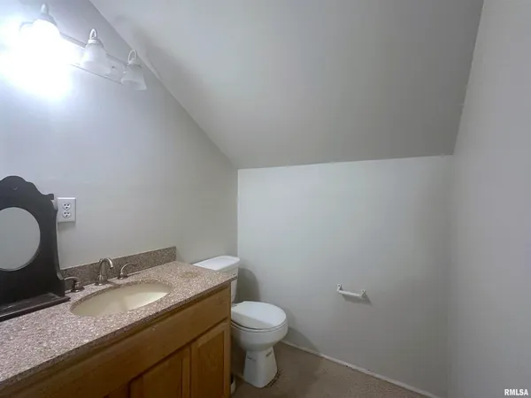 a bathroom with a granite countertop toilet and a sink