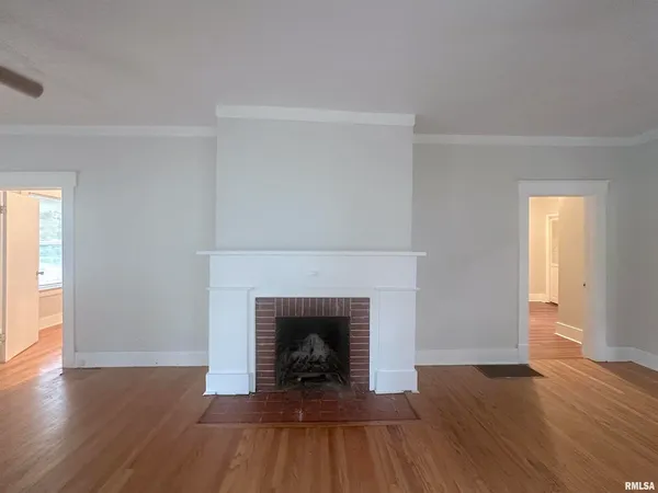 a view of an empty room with wooden floor and a fireplace