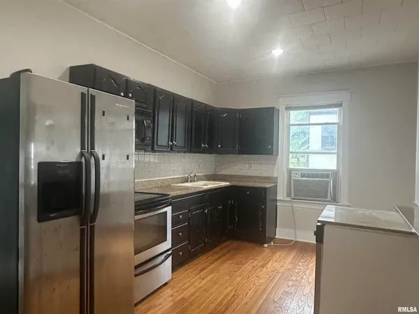 a kitchen with stainless steel appliances granite countertop a refrigerator a stove a sink and a microwave