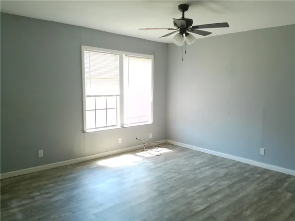 an empty room with a window and a ceiling fan