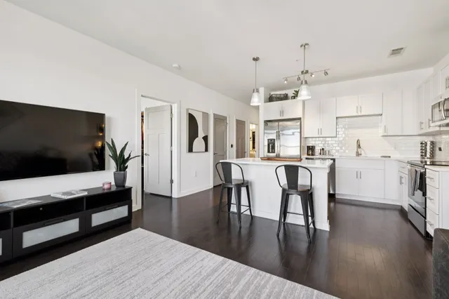 a living room with stainless steel appliances furniture and a flat screen tv
