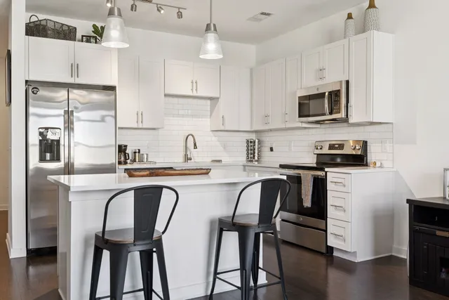 a kitchen with stainless steel appliances granite countertop a table chairs microwave and sink