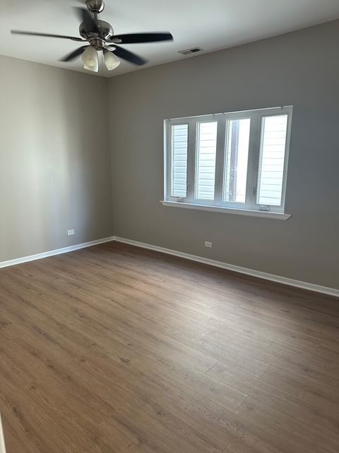 2956 North Hamlin Avenue, Unit 2R Chicago, IL 60618 - Photo 4 of 9 an empty room with wooden floor fan and windows