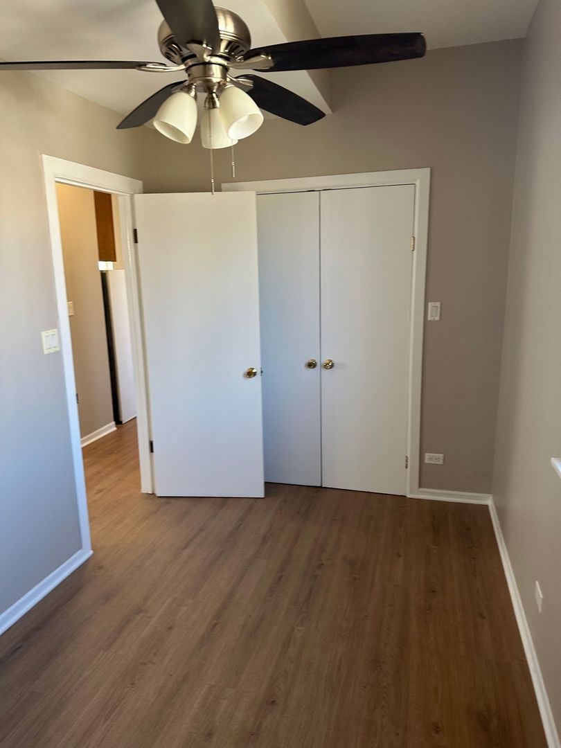 2956 North Hamlin Avenue, Unit 2R Chicago, IL 60618 - Photo 5 of 9 a view of an empty room with wooden floor and a ceiling fan