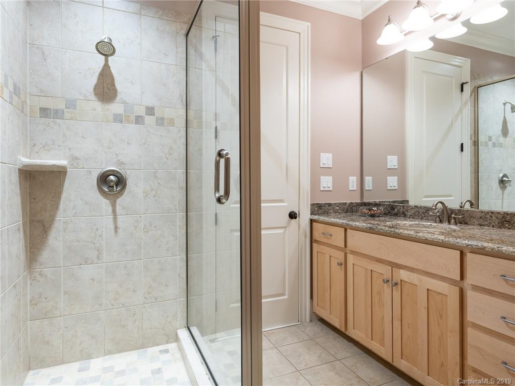 18424 Nantz Road Cornelius, NC 28031 - Photo 39 of 47 a bathroom with a granite countertop sink a mirror and shower