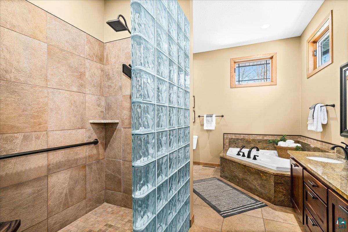 92598 Spells Road Sturgeon Lake, MN 55783 - Photo 29 of 60 Bathroom featuring walk in shower, a garden tub, vanity, and light tile patterned floors