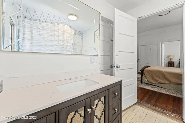a bedroom with a bed next to a window with wooden floor
