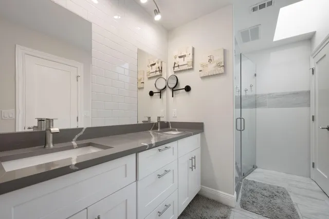 a bathroom with a granite countertop sink a mirror and shower