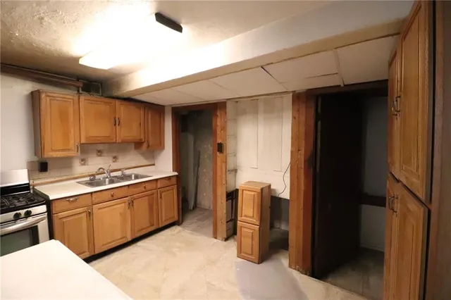 a kitchen with stainless steel appliances granite countertop a refrigerator a sink dishwasher a stove and white countertops with wooden floor