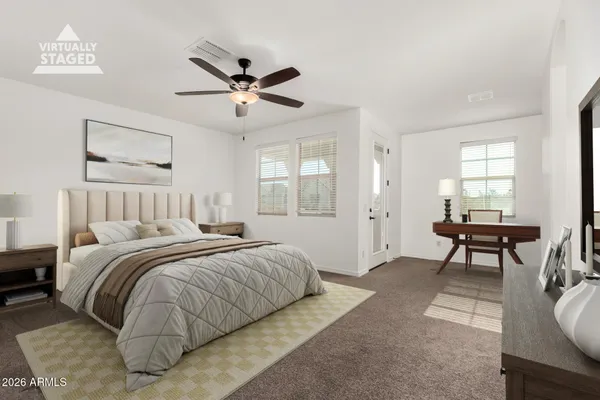 a spacious bedroom with a bed a table and windows