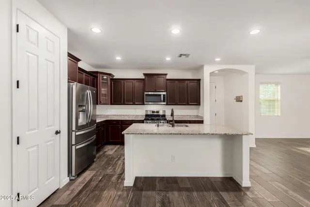 a kitchen with stainless steel appliances granite countertop a refrigerator and a stove top oven