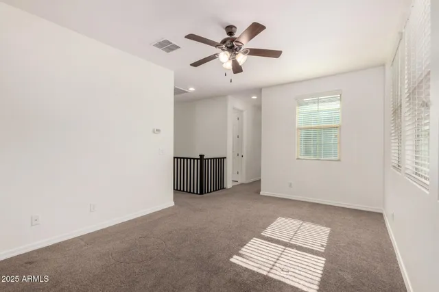 an empty room with windows and ceiling fan