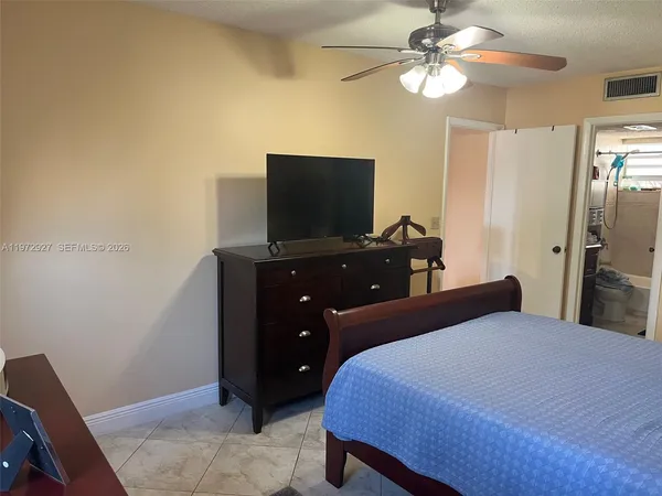 a bedroom with a bed and a flat tv screen on dresser