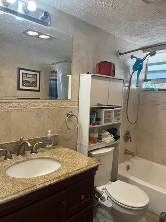 a bathroom with a granite countertop toilet sink and mirror