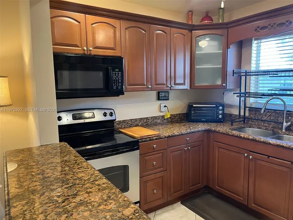 a kitchen with stainless steel appliances granite countertop a stove a sink and a microwave