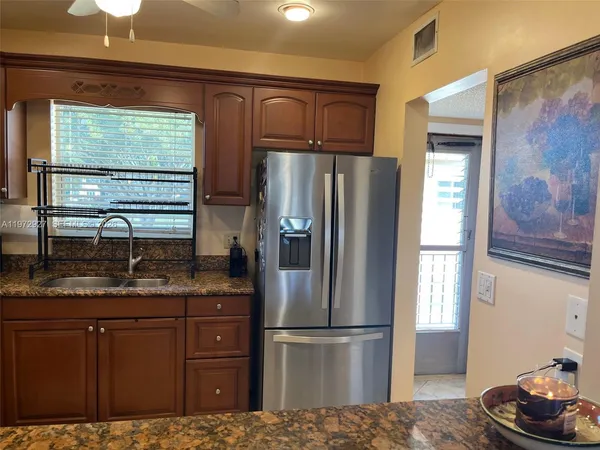 a kitchen with stainless steel appliances granite countertop a refrigerator and a sink