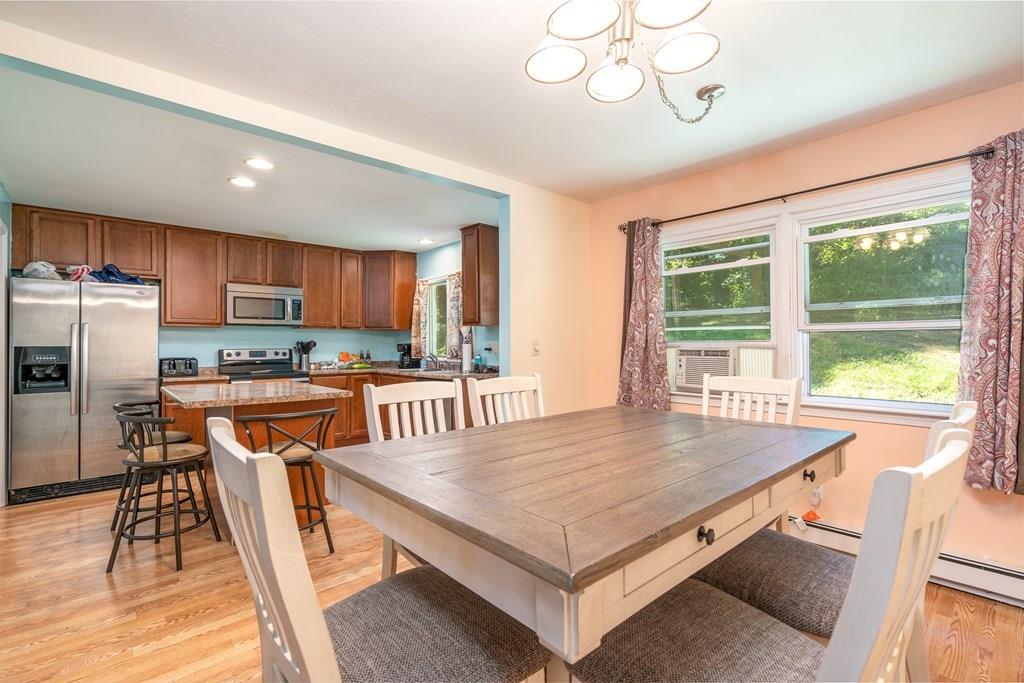 717 Florence Road Northampton, MA 01062 - Photo 7 of 27 a kitchen with stainless steel appliances granite countertop a stove a refrigerator a sink a dining table and chairs with wooden floor