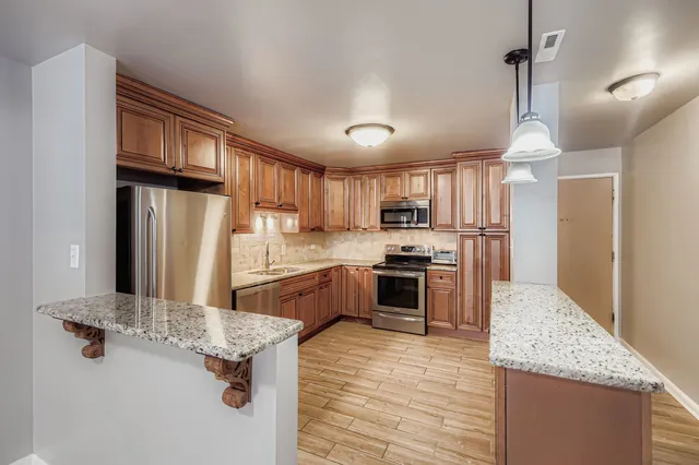 a kitchen with stainless steel appliances granite countertop a sink refrigerator and cabinets