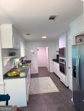a kitchen with stainless steel appliances granite countertop a refrigerator oven a sink dishwasher and white cabinets with wooden floor