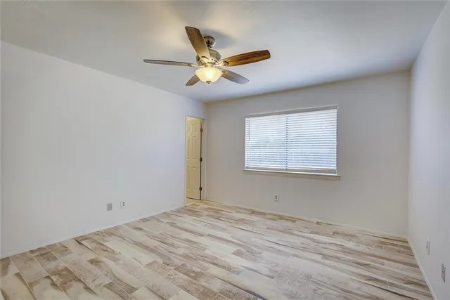 a view of empty room with wooden floor and ceiling fan